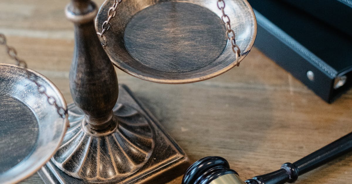 Justice scales and gavel on wooden surface with legal books