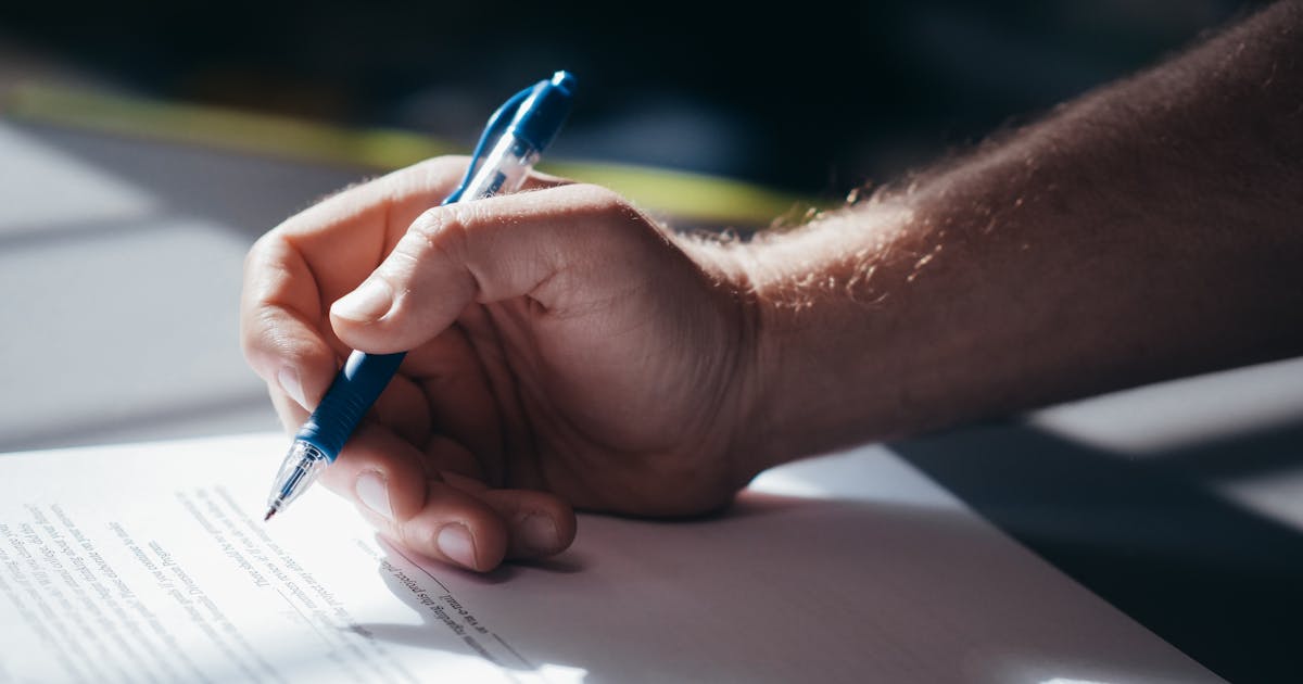 Person signing a legal document with a pen, representing prior express written consent